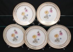 Porcelana Real, Mauá - SP(Fundada em 1943 por Fritz Erwin Schmidt). Elegante conjunto de pratos para sobremesa em porcelana nacional da década de 1950/60; esmaltagem vítrea na cor branca, orla circundada por faixa de acabamento nacarado, sobreposta por barrado contínuo de leques estilizados, guirlandas e frisos em douradura, centro dotado de bela composição botânica em estampagem policromada, predominando as tonalidades preta, rosa, azul e amarelo. Marca manufatura no verso. Composto de cinco(05) unidades. Medida: Diam.: 19 cm.