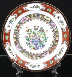 Prato de coleção em porcelana chinesa, esmaltação branca, decoração policroma aplicada sobre esmalte, apresentando reserva central com vaso florido, aves, borboletas e motivos fitomórficos. Aba ornamentada por faixas geométricas, volutas e reservas florais em vermelho-ferro, verde, azul, amarelo e preto, com realces dourados. Verso marcado Hand Painted Decoration  Made in China. Medida: Diam.:
