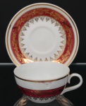 Porcelana Schmidt - Brasil(Fundada em 1945). Belíssimo xícara para chá em porcelana nacional da década de 1960/70; bojo hemisférico e alça lateral curvada, esmaltagem vítrea na cor branca, decorado com faixas de tom rubi e ornamentação em douradura aplicada, formando cercaduras de arabescos, elementos fitomorfos e rendilhados estilizados; bordas contornadas por filetes à ouro, padrão decorativo integralmente replicado no pires. Marca da manufatura no verso. Medidas: Xícara: Alt.: 5 x Comp.: 12 x Larg.: 9,5 cm. ; Pires: Diam.: 14,5 cm.