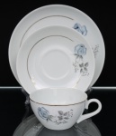 Porcelana Schmidt - Brasil(Fundada em 1945). Trio para chá em porcelana nacional, esmaltagem vítrea na cor branca, dotado de rica decoração com padrão de flores em estampagem, predominando as tonalidades azul, cinza e preto, realçado com frisos em douradura; bojo hemisférico e alça lateral em voluta. Padrão decorativo replicado no pires e no prato. Marca da manufatura ao fundo.  Medidas: Xícara: Alt.: 5 x Comp.:12 x Larg.: 9,5 cm. ; Pires: Diam.: 14,5 cm. ; Prato: Diam.: 18,5 cm.