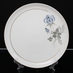 Porcelana Schmidt - Brasil(Fundada em 1945). Prato para serviço em porcelana nacional, esmaltagem vítrea na cor branca, dotado de rica decoração com padrão de flores em estampagem, predominando as tonalidades azul, cinza e preto, realçado com frisos em douradura. Marca da manufatura ao fundo. Medida: Diam.: 27 cm.