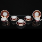 Porcelana Schmidt - Brasil(Fundada em 1945). Belíssimo conjunto de xícaras para café em porcelana nacional da década de 1960/70; bojo hemisférico e alça lateral curvada, esmaltagem vítrea na cor branca, decorado com faixas de tom rubi e ornamentação em douradura aplicada, formando cercaduras de arabescos, elementos fitomorfos e rendilhados estilizados; bordas contornadas por filetes à ouro, padrão decorativo integralmente replicado no pires e no prato. Marca da manufatura no verso. Composto: Medidas: Xícara: Alt.: 3,5 x Comp.: 9 x Larg.: 7 cm. ; Pires: Diam.: 11 cm.