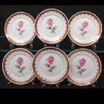 Porcelana Schmidt - Brasil(Fundada em 1945). Conjunto de pratos para sobremesa em porcelana nacional da década de 1960/70; esmaltação branca, decorado com reserva floral em policromia representando rosas e botões, complementadas por folhagens em tons de cinza, borda ornamentada com faixa de tonalidade bordô e elementos rendilhados aplicados em douradura. Marca da manufatura no verso. Composto de seis(06) unidades. Medidas: Diam.: 17 cm.