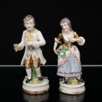 Duas(02) esculturas representando figuras masculina e feminina em trajes de época, executadas em porcelana moldada e policromada com aplicação de douração. Marcadas na base Vieira de Castro  Rio. Medidas: Alt.: 17 x Diam.: 7 cm.
