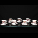 Porcelana Schmidt - Brasil(Fundada em 1945). Xícaras para café em porcelana nacional da década de 1960/70; esmaltação branca,  decorado com reservas florais em policromia representando rosas e botões, complementadas por folhagens em tons de cinza, borda ornamentada com faixa de tonalidade magenta e elementos rendilhados aplicados em douradura; bojo obcônico sobre base circular, alça lateral estilizada. Marca da manufatura ao fundo. Medidas: Xícara: Alt.:6 x Comp.: 8,5 x Larg.: 6,5 cm; Pires: Diam.: 11 cm.
