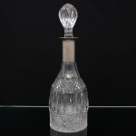 Garrafa licoreira em cristal lapidado, corpo de formato campanular facetado, decorado com faixas de motivos geométricos em relevo e lapidação tipo diamante. Gargalo alongado com colarinho metálico e tampa original em cristal lapidado em forma de botão. Medidas: Alt.: 35 x Diam.: 11 cm.