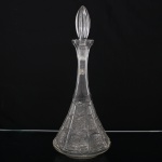 Garrafa para licor em cristal lapidado, corpo de formato cônico com gargalo alongado, decorada por reservas geométricas compostas por estrelas, rosáceas e frisos lapidados. Tampa original em cristal facetado em forma de gota alongada. Medidas: Alt.: 40 x Diam.: 16,5 cm.