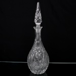 Garrafa licoreira em cristal moldado e lapidado, corpo bojudo com reservas ovais ornamentadas por motivo floral em relevo, pescoço facetado e gargalo alongado. Tampa original em cristal lapidado de formato prismático. Medidas: Alt.: 44,5 x Diam.: 13,5 cm.