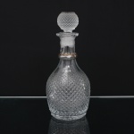Garrafa licoreira em vidro moldado, de corpo bojudo revestido por decoração em relevo tipo diamante(hobnail), pescoço alongado com anel aplicado de tonalidade âmbar e tampa texturizada, de formato esférico. Medidas: Alt.: 25 x Diam.: 11 cm.