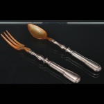 Christofle, Paris - França(Fundada em 1830 por Charles Christofle).Dois(02) talheres para serviço de salada confeccionadas em metal espessurado à prata, fabricação francesa do início do século XX, executado ao estilo do período Louis Philippe. Padrão "Chinon", usado a partir de 1862, conhecido anteriormente como "filet" ou "vieux Paris". Cabo apresenta "ombros" e margem contornada por frisos de terminação cordiforme sobre extremo arredondado. Lâmina em material sintético imitando chifre. Marca da manufatura puncionada no verso do cabo. Medidas colher: Comp. 29 cm. ; Comp.: 29 cm.