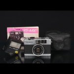 Câmera fotográfica Yashica 35-ME, Japão, para filme 35 mm, corpo em metal revestido, equipada com objetiva Yashinon 38 mm f/2.8, acompanhada de flash eletrônico Frata 300, estojo de transporte original em couro sintético e manual de instruções. Fabricação Japonesa da década de 1970. Não foi testado, sem garantias de funcionamento, apresenta marcas de uso e desgastes.Medidas: Alt.: 14,5 x Comp.: 11,5 x Larg.: 5 cm.