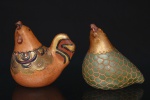 Duas(02) esculturas zoomórficas representando galináceos, entalhadas em madeira e policromadas à mão. Compostas por uma galinha e uma ave estilizada, apresentam decoração pintada em tons terrosos, verde e dourado, com motivos geométricos e plumagem estilizada em relevo. Apresentam desgaste da policromia, marcas de uso compatíveis com o tempo. Alt.: 13 x Comp.: 15,5 x Larg.: 9,5 cm. ; Medida verde: Alt.: 13,5 x Comp.: 16,5 x Larg.: 9,5 cm.