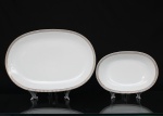 Porcelana Renner, Porto Alegre - RS(Fundada em 1937). Duas(02) travessas oblongas em porcelana nacional da década de 1960/70; esmaltação na cor branca, borda ornada por cercadura em meandro contínuo, de tonalidade cinza, e sucessão de quadrados duplos em douração aplicada. Marca da manufatura no verso. Medidas maior: Comp.: 37 x Larg.: 25 cm. ; Medidas menor: Comp.: 23,5 x Larg.: 16,5 cm.