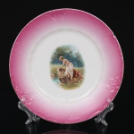 Prato de coleção em porcelana francesa Jean Pouyat, Limoges, com aba moldada em relevo radial, esmaltação rosa degradê e filete dourado na borda. Decorado ao centro com cena pastoral representando figura feminina seminua junto a curso d'água em paisagem campestre, executada em policromia por decalcomania. Produção do final do século XIX ou início do século XX, vinculada ao repertório decorativo Art Nouveau. Apresenta pequeno bicado na borda, vide foto. Medida: Diam.: