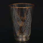 Vaso em vidro incolor de formato obcônico, decorado com pintura esmaltada e douração geométrica composta por losangos reticulados e painéis preenchidos por trama ondulada branca, arrematado por filete dourado no bordo. Medidas: Alt.: 20,5 x Diam.: 14,5 cm.