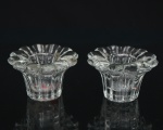 Par de castiçais baixos em cristal moldado, de formato floral, com borda recortada em pétalas e corpo facetado. Medidas: Alt.: 5 x Diam.: 8 cm.