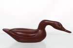 Escultura de ave aquática estilizada, executada em material sintético marmorizado em tonalidade castanho-avermelhada, olhos aplicados e composição de linhas fluidas inspiradas no desenho modernista. Medidas: Alt.: 17 x Comp.: 49,5 x Larg.: 13 cm.