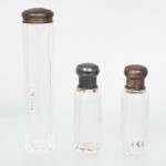 Conjunto composto por três(03) frascos para toalete ou perfumaria, em cristal incolor facetado, de formato cilíndrico, com tampas em prata contrastada. Apresentam marcas de de garantia da prata de teor 800 milésimos. Medidas: Alt.: x Diam.: