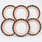 Porcelana, Steatita e Magnésia S/A, Campo Largo - PR(Fundada em 1954). Conjunto de pratos rasos em porcelana nacional da década de 1960/70; decoração em composição concêntrica, borda externa em esmalte preto ornada por reservas circulares em branco, intercaladas de maneira ritmada, contornada por filetes dourados. Faixa subsequente em esmalte rosa com sequência de grinaldas e elementos fitomorfos estilizados aplicados em douração. Cercadura interna em fundo nacarado com motivos radiais e palmetas estilizadas em ouro brunido. Calha delimitada por friso contínuo em douração rendilhada, formando sequência de volutas e elementos anelares. Contorno ondulado com acabamento dourado aplicado à borda. Composto de seis(06) unidades. Medida: Diam.: 24,5 cm.