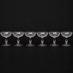 Belíssimo conjunto de taças francesas em cristal, do início do século XX, para serviço de champanhe; bojo hemisférico gravado com medalhão ovalado com composição simétrica formado por grinaldas suspensas, laçarias, festões e cartelas radiadas, circundada por friso perlado e motivos fitmorfos, borda com cercadura composta por enrolamento vegetalistas, palmetas estilizadas, volutas e elementos foliáceos repetidos em sequência linear; fuste balaústre, contendo anel intermediário, sobre base circular. Composto de seis(06) unidades. Medidas: Alt.: 10,5 x Diam.: 10 cm.