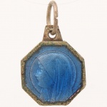 Medalha devocional octogonal confeccionada em prata, esmaltada na cor azul, apresentando no anverso perfil da Virgem Maria e, no reverso, representação da aparição de Nossa Senhora de Lourdes a Santa Bernadette. Argola de suspensão integrada. Medida: 0,7 cm.