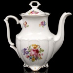 C.T. Tielsch, Walbrzych (antiga Altwasser) - Polônia. Belíssimo bule para café em porcelana polonesa. c.1940/50; esmaltagem vítrea de tom marfim, decorado com composição floral em estampagem policromada, bordas contornadas por friso em douradura; bojo oval relevado com sucessão de gomos verticais, tampa ligeiramente abaulada, bico vertedor curvilíneo de ponta recortada, asa lateral e paga da tampa formada por volutas, base sobre quatro pés recortados. Marca da manufatura ao fundo. Medidas: Alt.: 20 x Comp.: 20,5 x Larg.: 12 cm.
