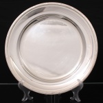 FRACALANZA. Elegante bandeja confeccionada em metal espessurado à prata, formato circular, centro ligeiramente rebaixado, borda relevada com fileira de frisos intercaladas por fitas cruzadas, ornato obtido através da técnica do cinzelado. Marca da manufatura no verso. Apresenta marcas de uso. Medida: Diam.: 30,5 cm.
