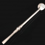 Bomba para chimarrão confeccionada em metal prateado, haste tubular e passador relevado com folhagens, patilha oval perfurada, boquilha achatada(apresenta pequena amolgadela). Medida: Comp.: 20 cm.