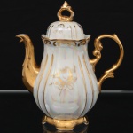Porcelana Real, Mauá - SP (fundada em 1943 por Fritz Erwin Schmidt). Bule para café em porcelana nacional, década de 1960/70, corpo moldado em gomos com acabamento nacarado, decorado em douração aplicada à mão com motivos vegetalistas estilizados. Apresenta bocal e alça vazados de desenho rocaille, tampa encaixada com pega vazada e base recortada. Marca da manufatura no verso. Medidas: Alt.: x Comp.:  x Larg.: cm.