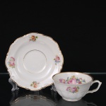 C.T. Tielsch, Walbrzych (antiga Altwasser) - Polônia. Belísima xícara para chá em porcelana polonesa da década de 1390/40; esmaltagem vítrea na cor branca, decorada em policromia com composição floral constituídas por rosas, tulipas e flores campestres, distribuídas em reservas no interior da xícara, no bojo e no pires, aplicada em estampagem; bordas realçadas por filetes dourados. Marca da manufatura no verso. Medidas: Xícara: Alt.: 5 x Comp: 12 x Larg.: 10 cm. ; Pires: Diam.: 15 cm.