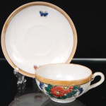 Xícara para chá em porcelana oriental, dito casca de ovo", esmaltação branca, bojo hemisférico sobre base circular, alça lateral em voluta; corpo esmaltado com decoração policroma de flores estilizadas em vermelho, azul e verde, acompanhadas de borboletas, borda circundada por faixa em tom ocre e filete preto. Medidas: Xícara: Alt.: 4 x Comp.: 10,5 x Larg.: 8,5 cm; Pires: Diam.: 13 cm.
