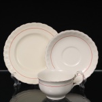 W.H. GRINDLEY, Staffordshire - Inglaterra(Fundada por William Harry Grindley em 1880). Trio para chá em faiança inglesa da década de 1940/50, padrão "Creampetal"; esmaltagem de tom marfim, decorado com frisos em douradura e tom coral, bojo hemisférico sobre base circular, asa lateral em voluta, bordas do pires e do prato relevadas com perolados e ondulações. Marca da manufatura no verso. Apresenta desgaste na douradura. Medidas: Xícara: Alt.: 5,5 x Comp. 12 x Larg.: 9,5 cm; Pires: Diam.: 14,5 cm; Prato: Diam.: 17,5 cm.