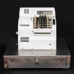 Máquina registradora mecânica Hugin, em metal esmaltado e aço inoxidável, com gaveta para numerário, teclado numérico e alfabético, visor contador e compartimento interno para bobina de papel. Utilizada para registro e controle de operações comerciais.  Medidas: Alt.: x cm. Comp.: x cm. Prof.: x cm.
