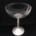 Champanheira em acrílico e metal, corpo de formato hemisférico apoiado sobre haste cilíndrica e base circular cônica. Utilizada para acondicionamento e serviço de garrafas de champanhe, espumante ou vinho em gelo. Design modernista. Medidas: Alt.: 74 x  Diam.: 55 cm. Estado conforme fotografias, apresenta oxidação na base.