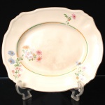 Alfred Meakin, Staffordshire - Inglaterra(Fundada em 1875, ativa até 1976). Travessa da década de 1930 em faiança inglesa, estilo e período Art Déco; esmaltagem de tom marfim, decorada com o padrão "Marigold", borda recortada e aba moldada, decorada com composição floral policromada e filetes em tonalidades verde e dourada. Marca da manufatura no verso. Medidas: Comp.: x Larg.: