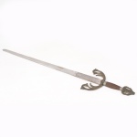 Espada decorativa modelo Tizona del Cid, de inspiração medieval espanhola, lâmina reta em aço com gravação de arabescos e motivos vegetalistas, guarda vazada em metal fundido com volutas estilizadas, empunhadura revestida em malha metálica e pomo vazado, exemplar inspirado na espada atribuída a Rodrigo Díaz de Vivar, El Cid. Apresenta desgastes e marcas de uso. Medida: Comp.: 102 cm.