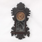 Ansonia Clock Company, Brookly, NY - EUA(Fundada em 1851): Relógio de parede do final do século XIX, circa 1894. Caixa em madeira de tom escurecido com moldura recortada, e lavrada com motivo fitomorfo, frente em vidro jateado com flores e elementos geométricos. Dial circular em papel sobre metal, dois furos, numeração romanda. Acompanha chave e pêndulo, gongo original. Não está funcionando.. Med.: Alt.: 63 x Comp.: 33 x Larg.: 10 cm.