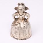 Antiga sineta de mesa confeccionada em metal espessurado à prata, executada na forma de camponesa com vestes de estilo vitoriano. Marca da manufatura ao fundo. Med.: Alt. 7,5 x Diam.: 4,5 cm.
