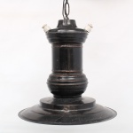 Luminária pendente industrial, confeccionada em metal pintado em preto, com cúpula circular escalonada e corpo central torneado, suspensa por corrente metálica. Apresenta dois isoladores elétricos em porcelana branca para fixação e condução da fiação dos pontos de luz laterais, característica funcional recorrente em luminárias industriais da primeira metade do século XX. Produzida em estilo industrial utilitário, utilizada em fábricas, oficinas, armazéns e estabelecimentos comerciais. Instalação elétrica adaptada, não testada. Apresenta desgastes, pontos de oxidação e marcas de uso. Medidas: