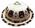 ENGLAND SÉC. XIX  - Rara queijeira em porcelana inglesa CROWN  by WILLIAM LOWE, fartamente adornada com flores policromadas com vibrante ouro sobre fundo azul. Tampa gomada com pega. Segunda parte do séc. XIX. Mede 20cm diâmetro.