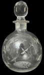 Garrafa em cristal artístico, de formato globular, decorada com delicada gravação em motivos de estrelas lapidadas. Acompanha tampa original facetada, também em cristal. Base com marca Margareth Duncan, tradicional manufatura ligada à produção de cristais artísticos. Peça elegante, provavelmente a licor, com acabamento refinado e boa transparência do cristal. Mede 17cm de altura.