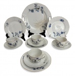 Conjunto de chá em porcelana europeia Vitoria Porcellite, composto por 4 xícaras com pires, pratos de sobremesa e prato maior para bolo, decoração floral em tons de azul com detalhes dourados. Peças com delicado relevo geométrico, bordas filetadas e marca de fábrica na base. Apresenta sinais de uso e desgaste do tempo, uma com frio de cabelo. Medida do maior 25 cm.