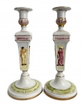 ITALIA - Par de castiçais em porcelana italiana Capodimonte, ricamente decorados com cenas clássicas de figuras humanas em relevo policromado, detalhes em douração e base trabalhada. Peças elegantes, de fino acabamento, típicas da tradição italiana decorativa do século XX. contorno em vibrante ouro. Mede 32 cm altura.