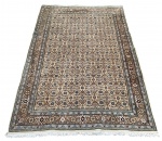 Tapete persa Mahi (Herati), com rico desenho geométrico repetitivo e bordadura floral detalhada, em paleta elegante de tons terrosos, azul e marfim. Produzido em lã de boa qualidade, apresenta excelente densidade e acabamento refinado, com franjas nas extremidades. Medidas: 304 x 195 cm.