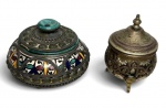 Conjunto decorativo composto por duas peças orientais: uma caixa em porcelana com montaria em metal, ricamente ornamentada com esmaltação policromada em padrão geométrico e floral, e um pequeno recipiente em metal com tampa, apoiado sobre três pés, com decoração em relevo. Peças de caráter decorativo, com influência do cloisonné. Em bom estado geral, com desgastes naturais do tempo. Possui discreto bucado em uma tampa. Medida do maior 11cm.