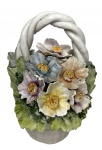 Cestinha decorativa em Capodimonte, ricamente modelada com flores policromadas em relevo e alça entrelaçada, sobre base texturizada simulando cestaria. Peça delicada, de caráter ornamental, com base revestida em feltro. Possui bicados nas pétalas. Mede 12x14cm.