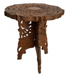 Coluna oriental em madeira nobre ricamente entalhada, apresentando tampo circular com decoração floral e arabescos em relevo. Base vazada com elegante trabalho artesanal e forte apelo decorativo, ideal para composições clássicas ou ambientes exóticos sofisticados. Mede 32 cm altura x 30 cm diâmetro.
