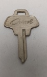 chave original Ford Corcel (1ª Geração), uma peça clássica de memorabilia automotiva. Este modelo específico, com a cabeça em formato trapezoidal e a grafia "Corcel" em letra cursiva, equipava os veículos fabricados entre 1968 e 1977, antes do lançamento do Corcel II.
