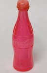 Mini Garrafinha Coca-Cola Glitter Rosa, que fez parte da famosa promoção "Miniaturas da Copa" ou campanhas promocionais de verão no início dos anos 2000. Diferente das garrafinhas de metal dos anos 90, esta linha apostou no plástico translúcido com brilho interno (glitter), sendo um item de apelo muito visual e nostálgico para quem viveu essa época.