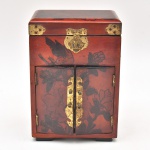 Antigo e lindo Porta joias, peça oriental, em madeira laqueada nas ocres vermelho e preto. Parte inferior com duas portas. Interior com duas gavetinhas. Parte superior com tampo reclinável. Interior forrado de tecido vermelho. Guarnições de metal amarelo. Med. 22 x 15 x 10,5 cm (A x C x L). Faltam cadeado e as chaves.